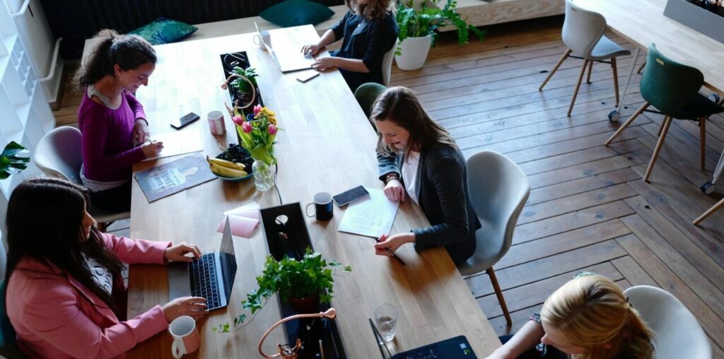 Junge Frauen arbeiten an Laptops an einem großen Tisch
