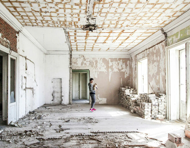 Eine Frau steht mit einem Baby in einem Haus, was gerade kernsaniert wird